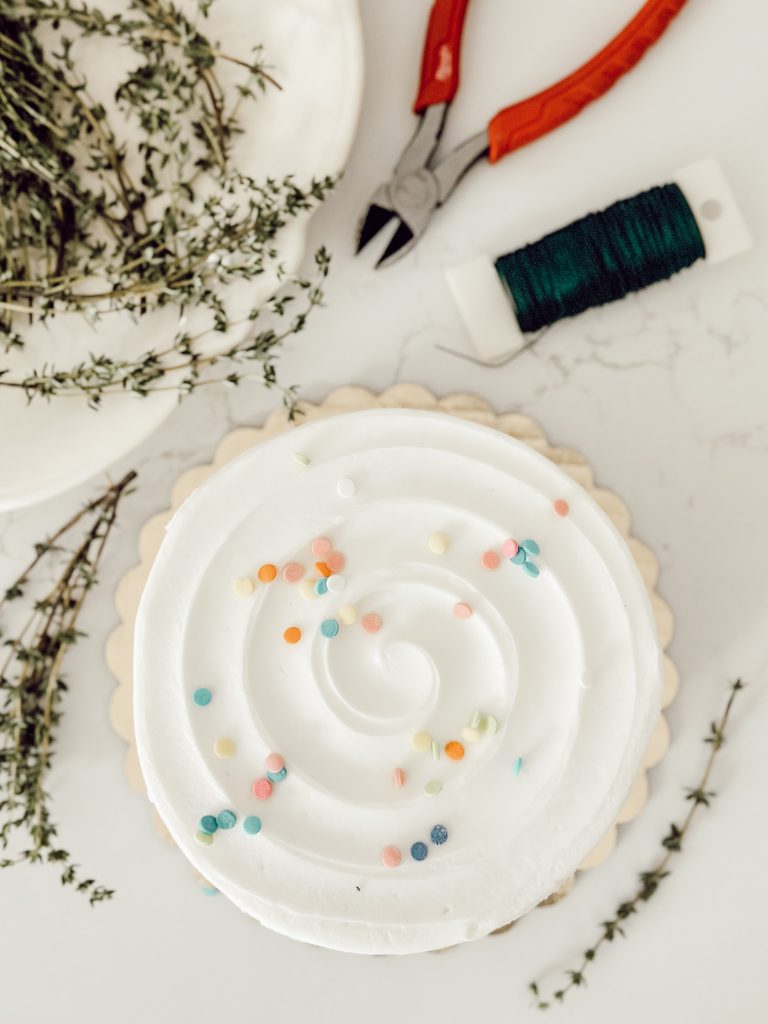 Materials for DIY cake topper include a cake, fresh thyme, floral wire, and pliers.