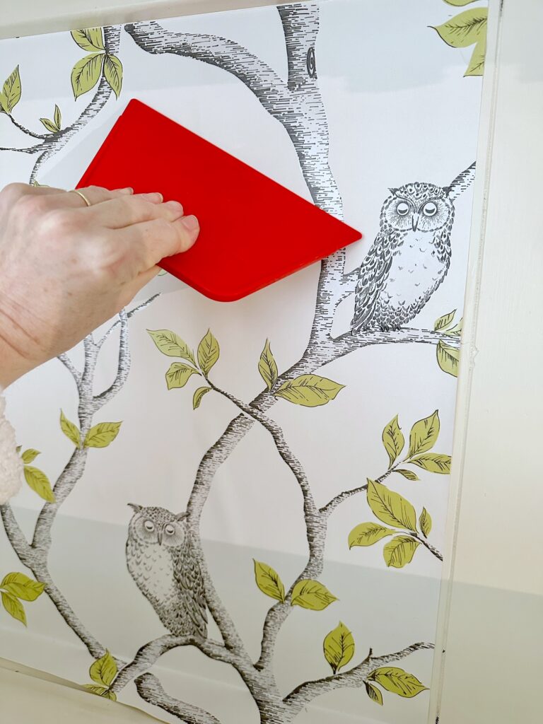 smoothing out the wallpaper with a red tool.