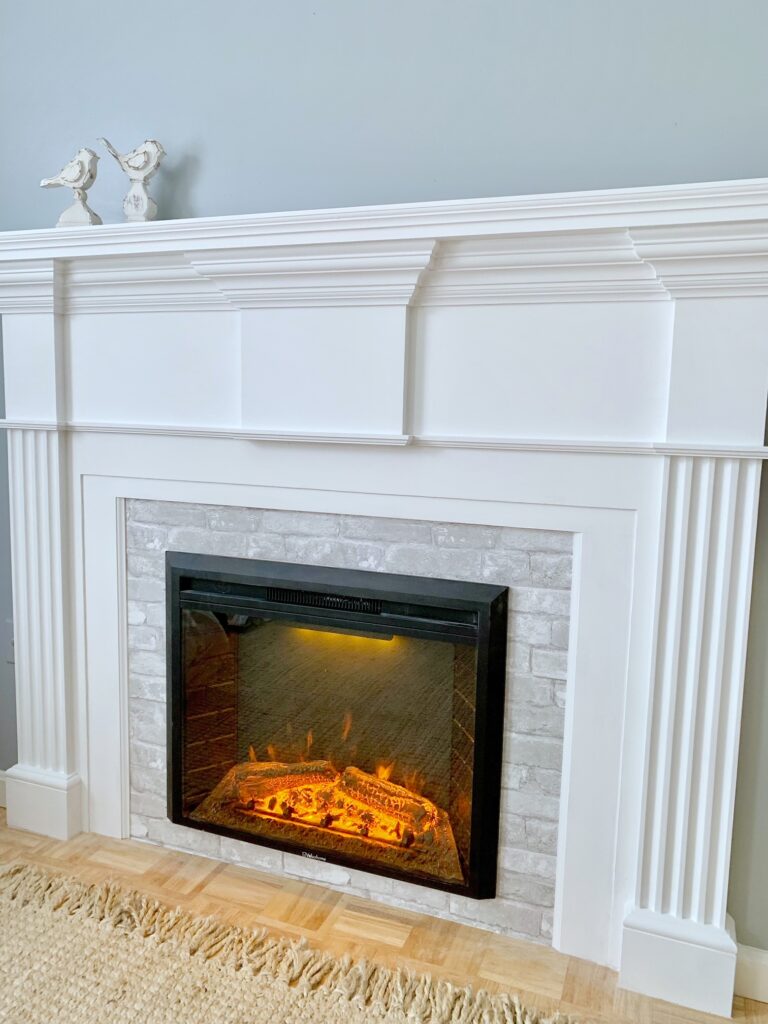 fireplace surround with insert and gray brick wallpaper. 