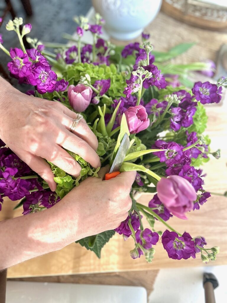 placing the purple tulips into the arrangement. 
