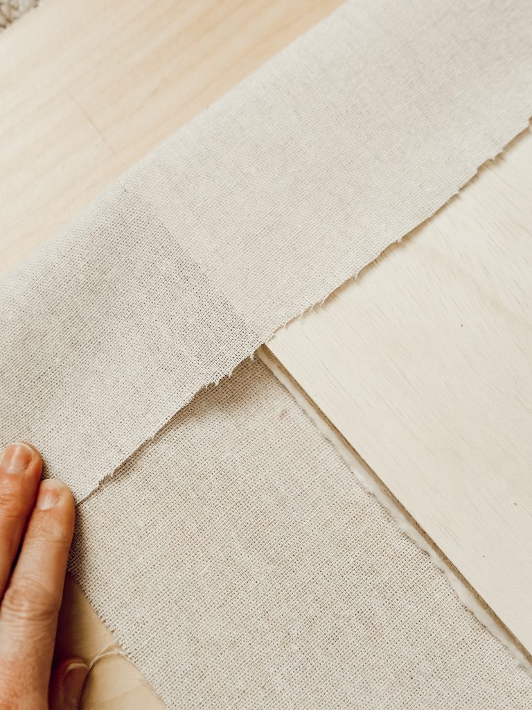 Homemade fabric memo board using fabric, ribbon, and plywood.