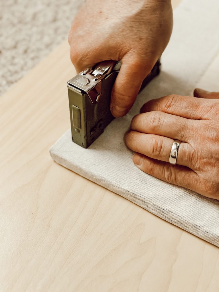 Pull the fabric taut and staple the corner of the memo board with a staple gun.