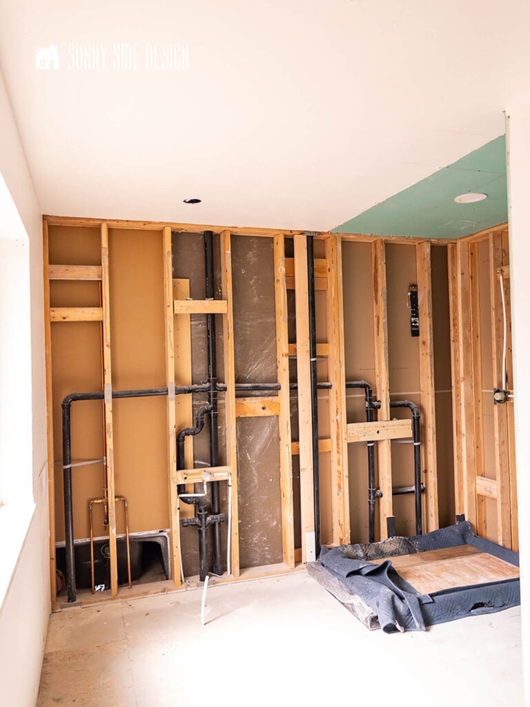 Framed wall with water lines and sewer plumbing pipes.